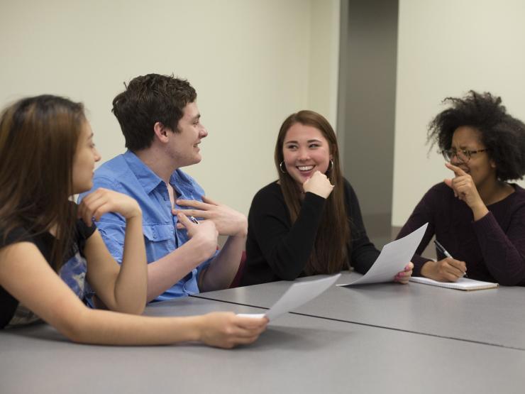 Students working around table, talking and smiling