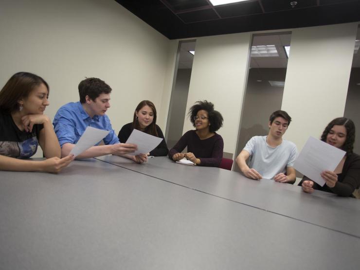 Group of students having a discussion around a table in a classroom