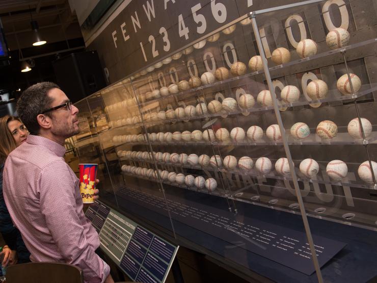 Two people looking at display case full of baseballs