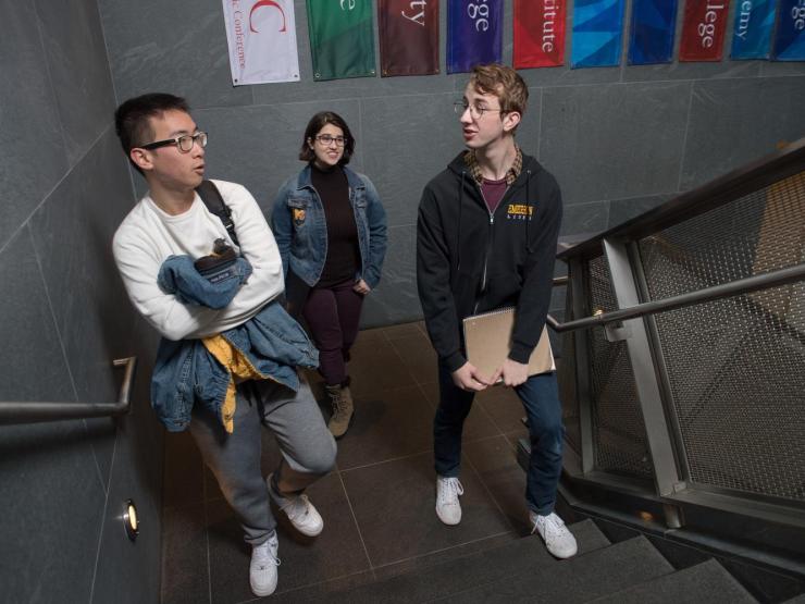 Three students climbing up a flight of stairs