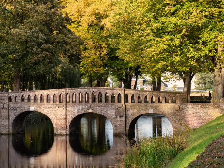 Kasteel Well campus bridge with river and trees surrounding