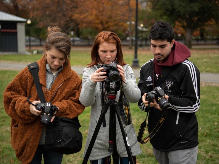 Group of three students inspecting their cameras and tripods