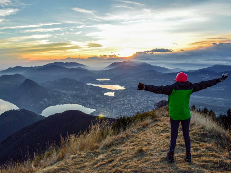 Person standing on mountain in Switzerland with their arms stretched out