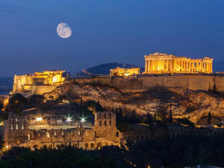 Parthenon ruins in Athens at night. The moon is shown in the sky