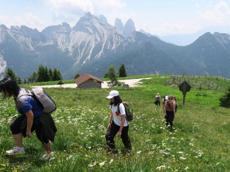 Students walking up a grassy hill with mountains in the background