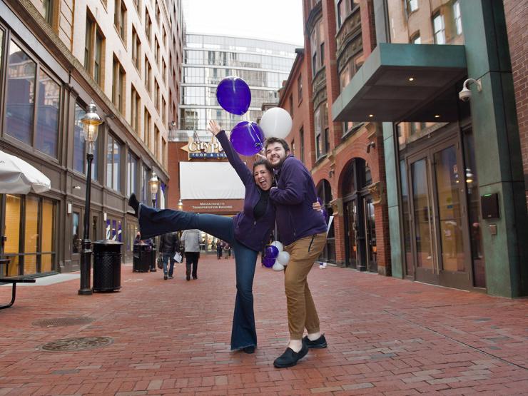 Two students holding purple and white balloons in Bolyston Place Alley