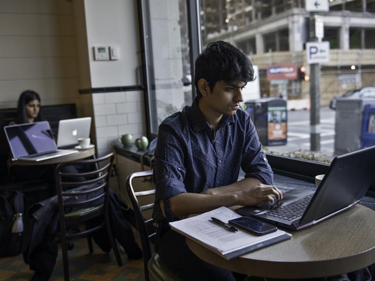 Student in digital content management class working on laptop in a cafe