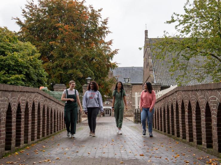 four students walking on a bridge at Kasteel Well