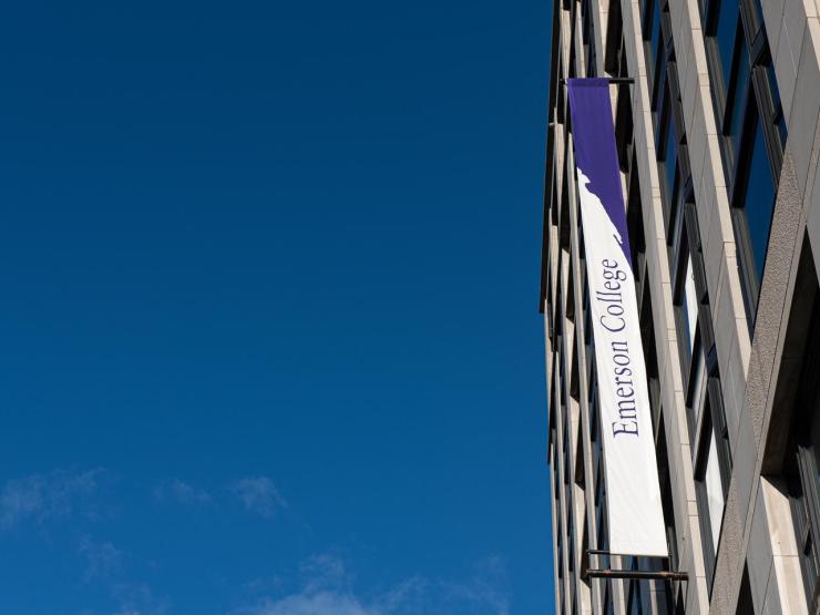 Purple and white Emerson College banners along a side of a campus building