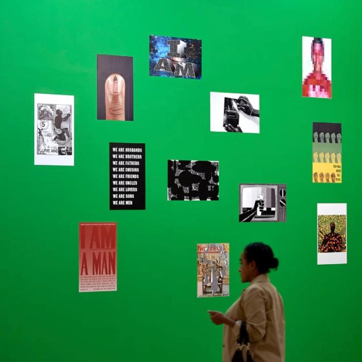 Gallery mock up shows many small posters on a green wall with a person looking at them