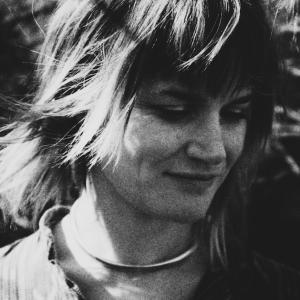 A black and white picture of a woman with shaggy hair looking down and smiling