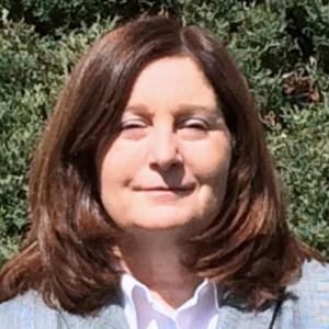 Headshot of Janice Pieroni standing outside in front of a hedge