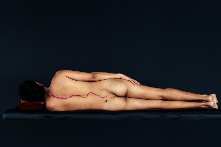 Photo by Emilio Rojas, Heridas Abiertas (to Gloria), 2014–ongoing. Digital photograph of a naked body facing away from the camera, lying on its side.