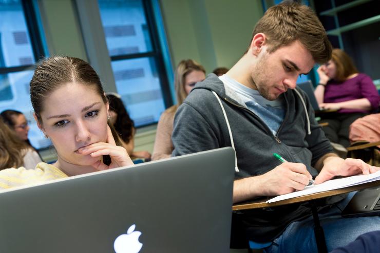 student on laptop and another one writing