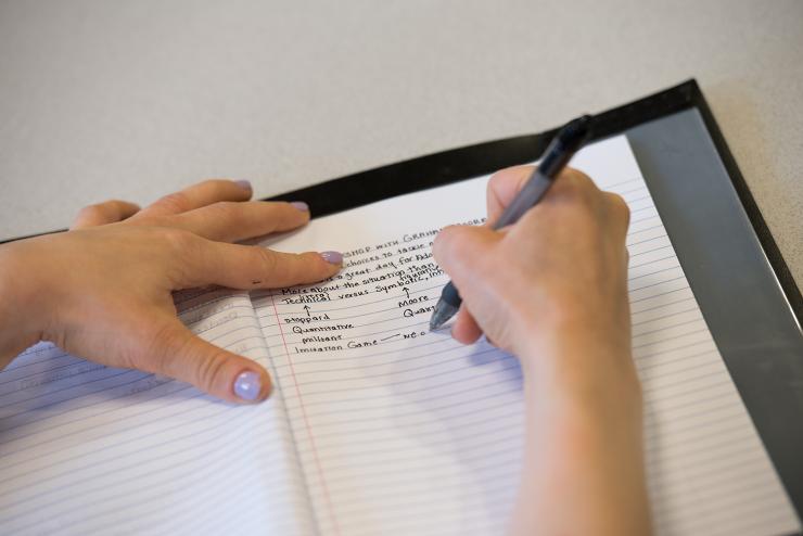 hands writing on notebook