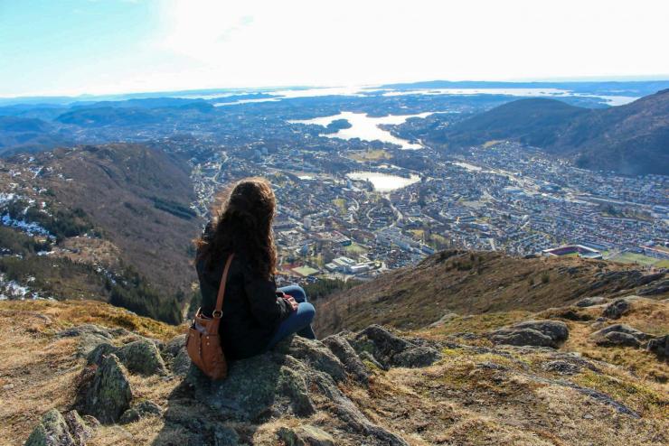 Person sitting on mountain top and looking at the valley