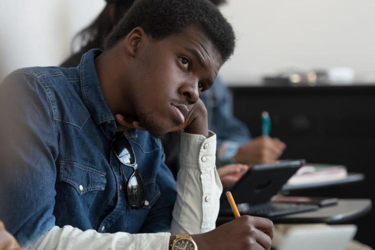 Student sitting in class, leaning on hand