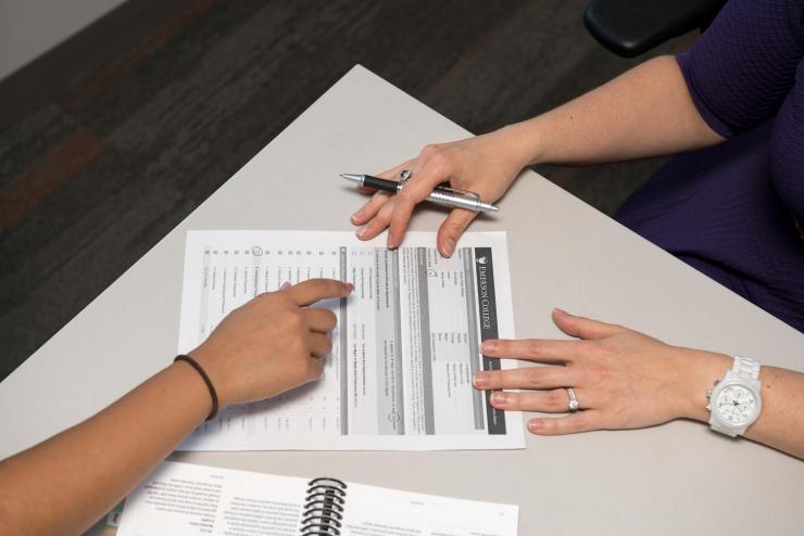 Close-up pf two people discussing paperwork and pointing at a document