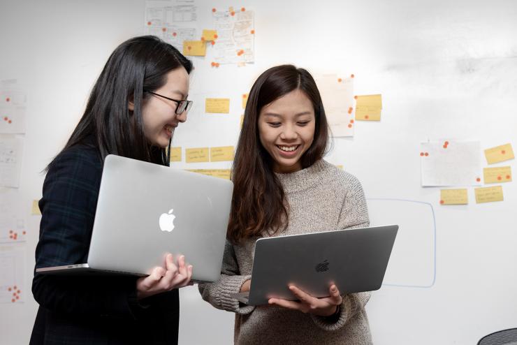 2 students hold laptops