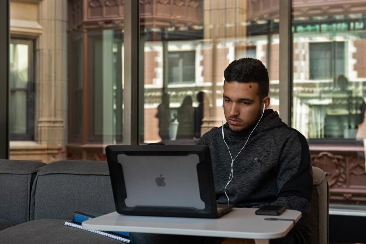 Student wearing earphones and working on laptop