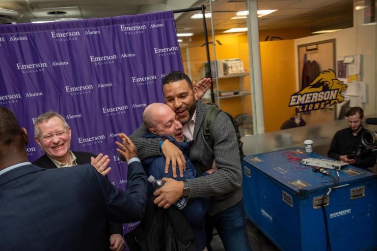 Alums hugging and greeting one another at an Emerson Lions alumni event