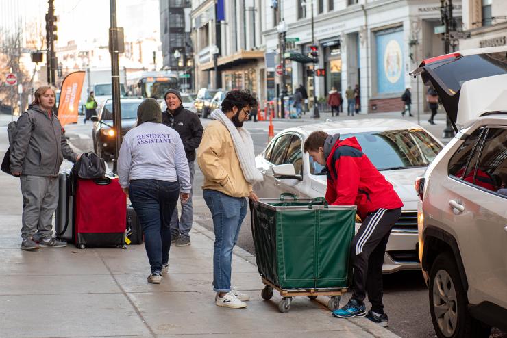 Students filling carts with their belongings on the street