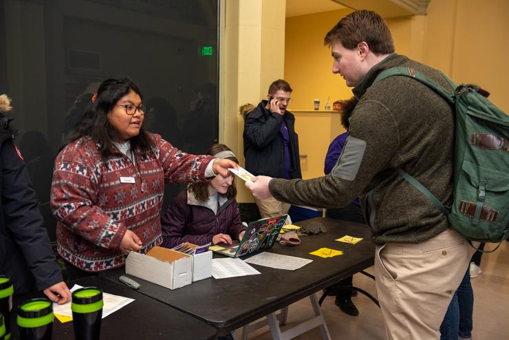 A student receiving a brochure from a resident assistant