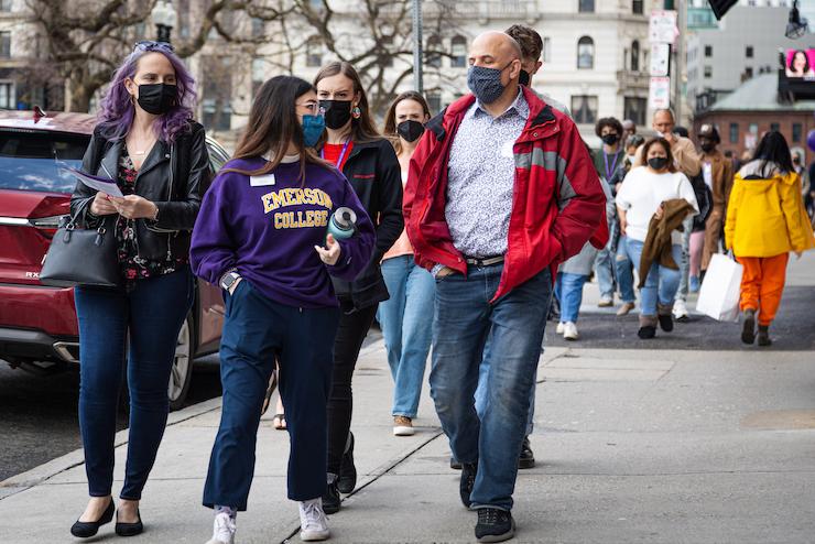 people wearing "Emerson" hoodie walking on campus