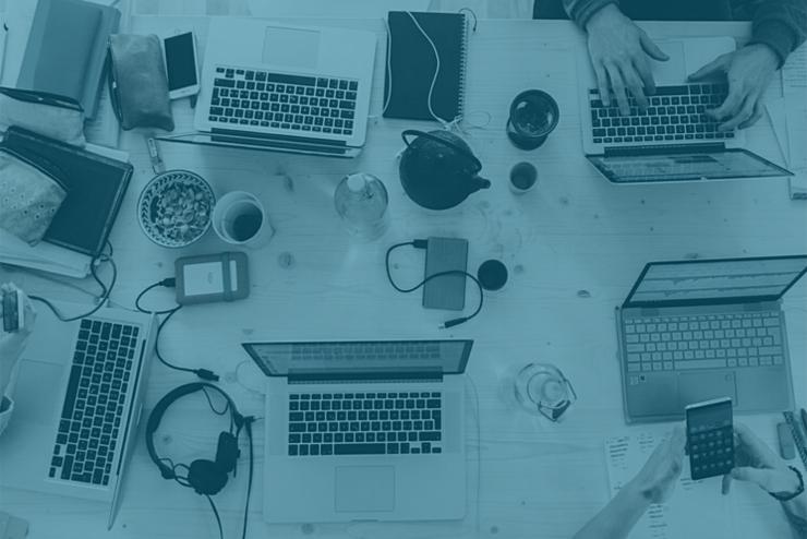 a desk with computers and various accessories laid out with hands typing