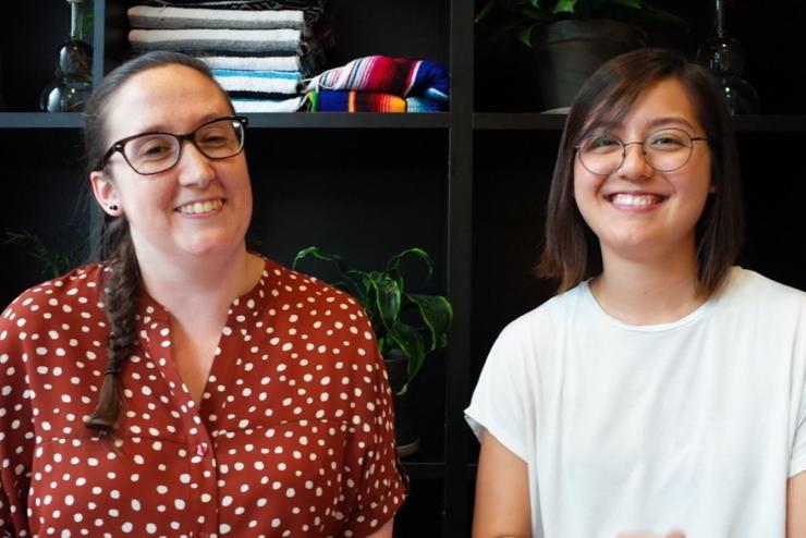 two ladies smile and pose in front of a bookcase