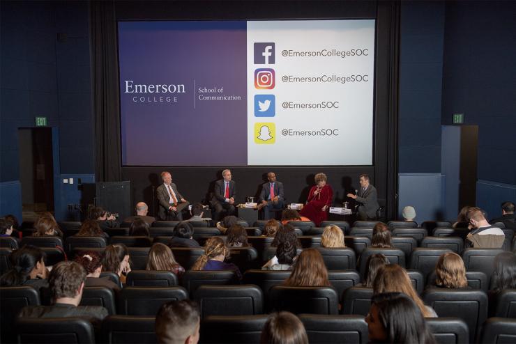 A presentation with the presenters showing a screen with social media tags