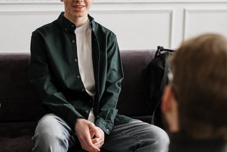 A person sitting on a couch talking to another