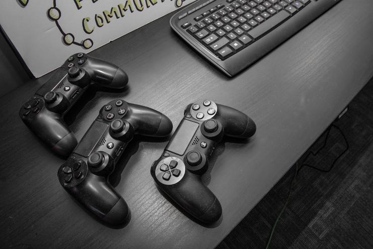 Three game consoles sitting on top of a table by a keyboard